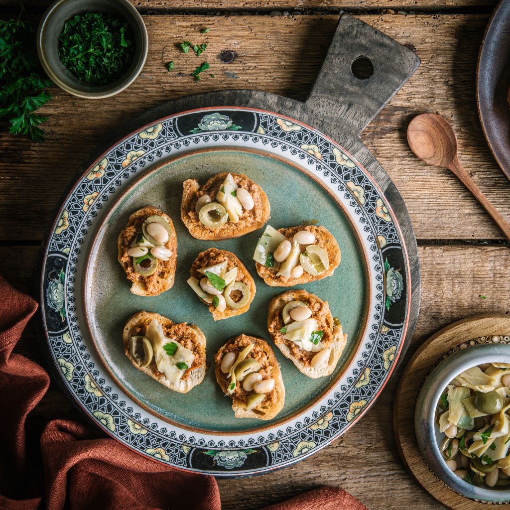 Vegan Sundried Tomato Pesto Crostini with white beans, artichokes & olives